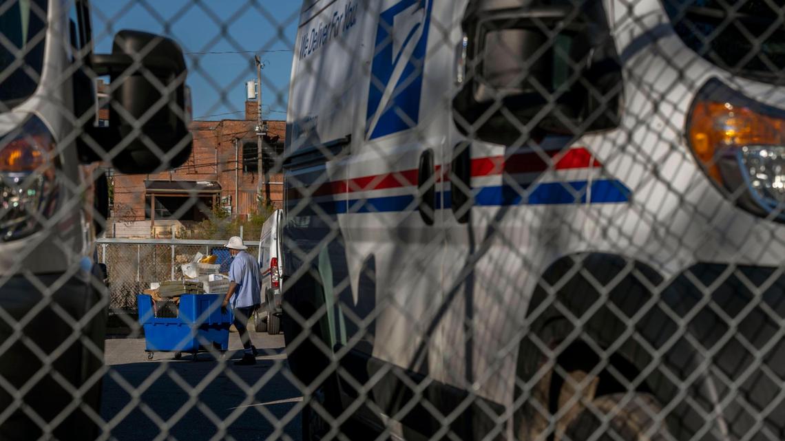 A Postal Service worker moves mail at a Kansas City area post office.