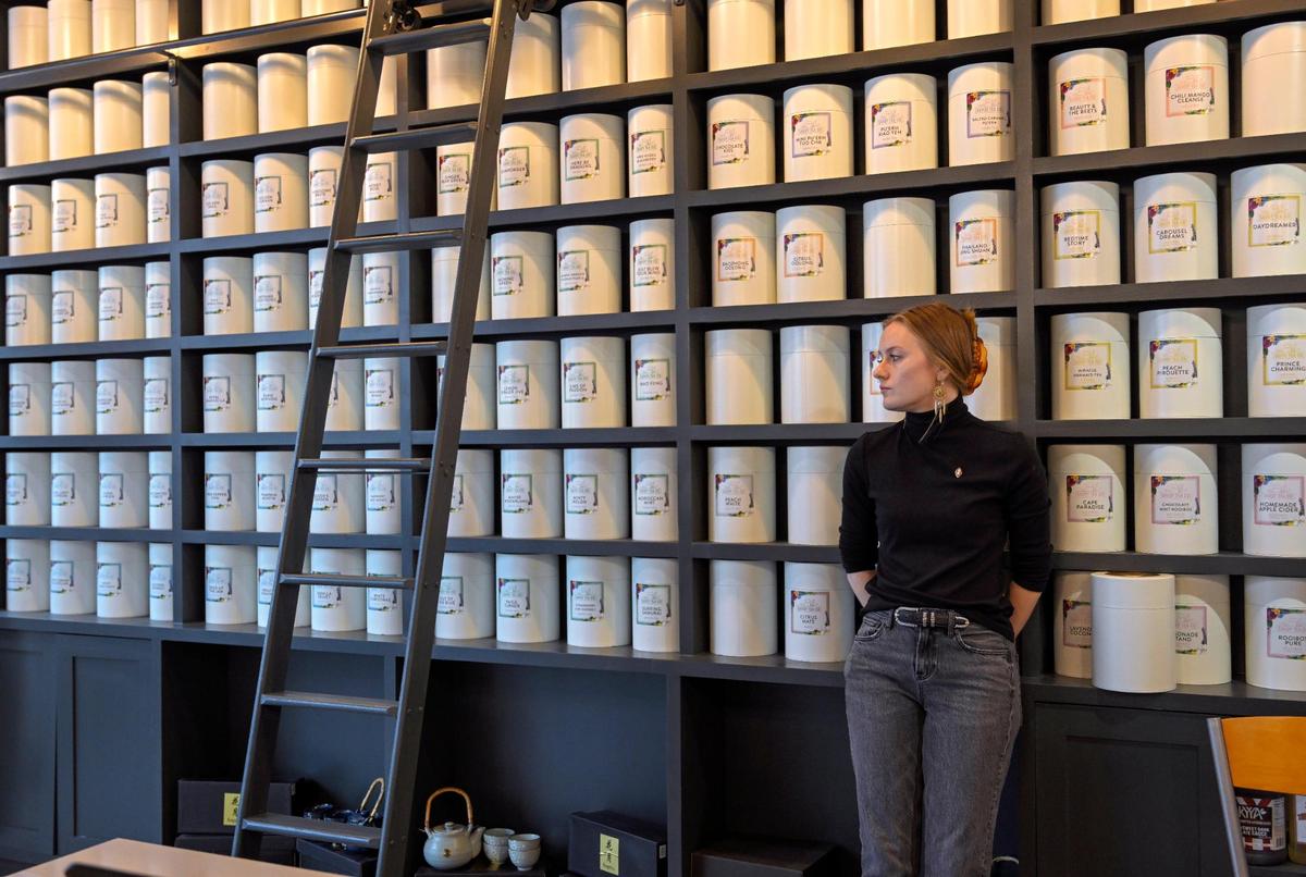 Tea barista Bailey McCulloch is perched near canisters of custom blends of loose tea at the new Savoy Tea Co.