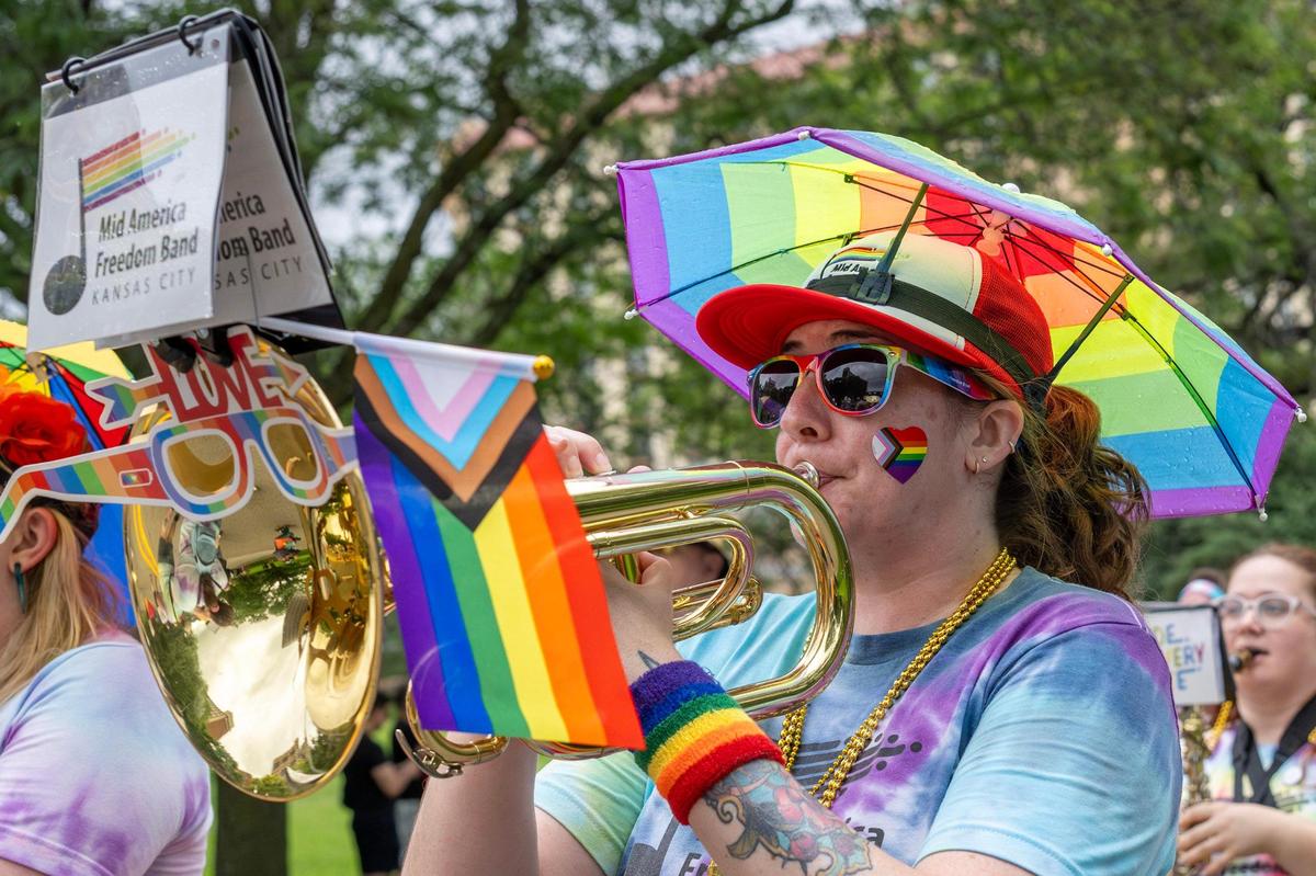A member of the Mid-American Freedom Band Kansas City plays a handheld brass instrument during the KC Pride Parade along Mill Creek Parkway.
