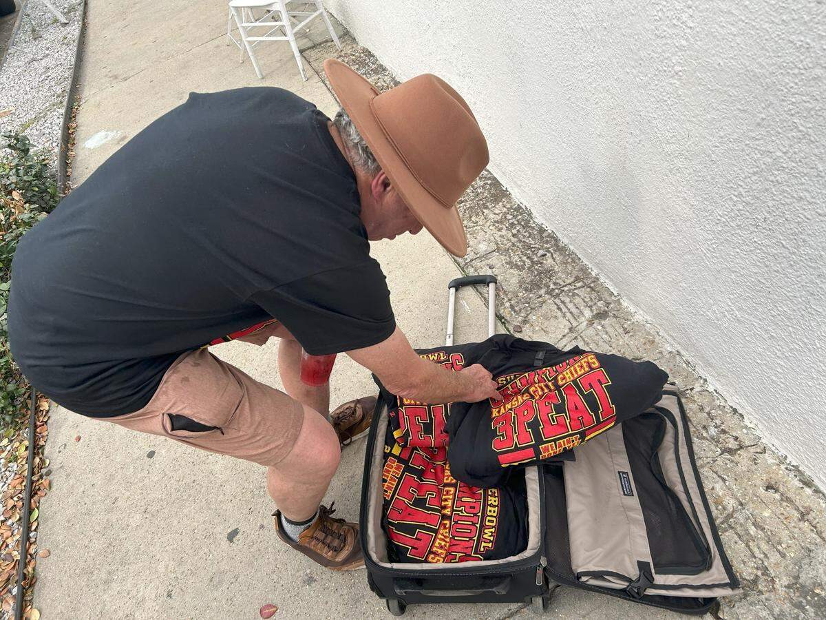 A bootlegger with unlicensed Chiefs T-shirts sells them out of a black suitcase in New Orleans.