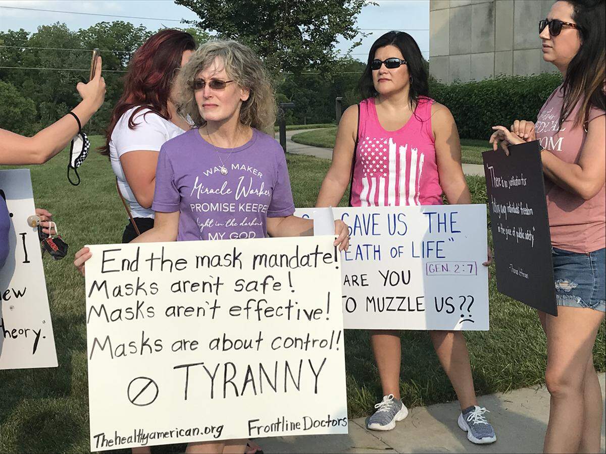 Protesters held signs falsely asserting that masks don’t protect against spread of the coronavirus.