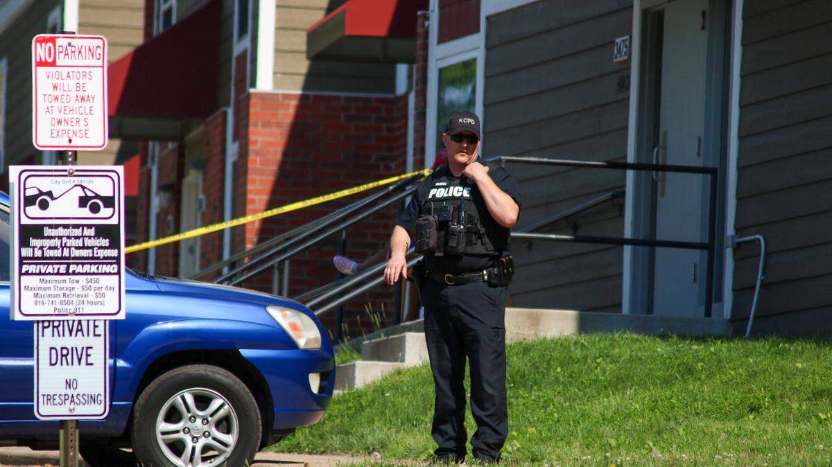 A Kansas City Police officer talks on his radio at the scene of a homicide Saturday. Police say one victim was killed after several people fired guns in an apartment complex.