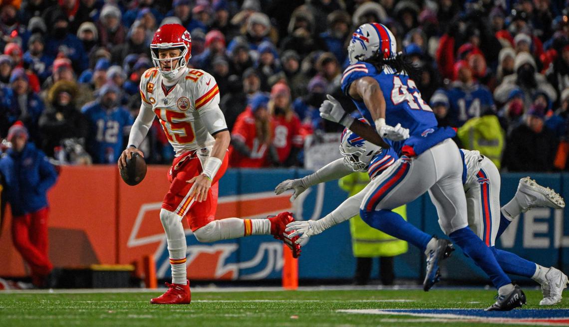Kansas City Chiefs quarterback Patrick Mahomes (15) looks for an open receiver as he is chased out of the pocket by a pair of Buffalo Bills defenders Sunday, Jan. 21, 2024, at Highmark Stadium in Orchard Park, New York.