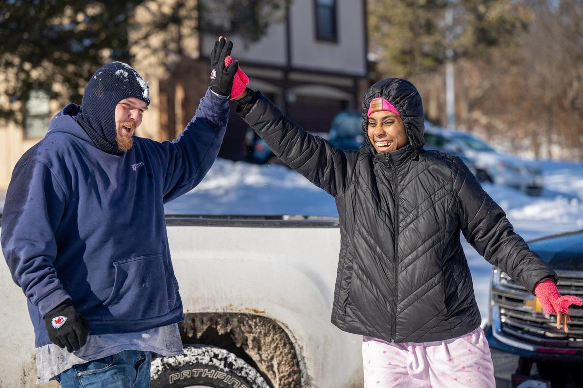 Corey Sutton of Kansas City, Kan. gets a high-five and smile from Mia Ford-Bailey after Sutton pulled her uncle’s vehicle from a snowbank on Tuesday near their home in Kansas City, Kansas.