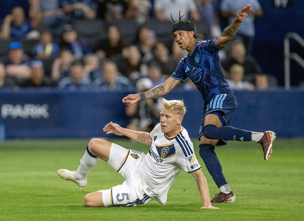 LA Galaxy defender Jakob Glesnes (5) looks on Sporting Kansas City forward Calvin Harris (11) reacts as his kick scored a goal in the second half at Sporting Park on Wednesday, May 13, 2026, 2026, in Kansas City, Kansas. Sporting KC defeated the LA Galaxy, 3-1.