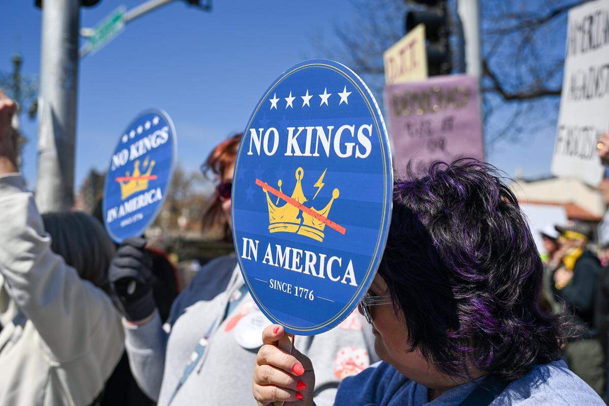 A protester holds up a “No Kings in America” sign during a No Kings rally against the Trump administration in Mill Creek Park near the Country Club Plaza on Saturday, March 28, 2026.