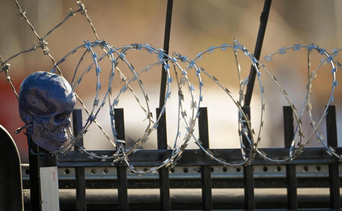 A painted skull sits on a fence topped with razor wire and barbed wire outside The Spott.