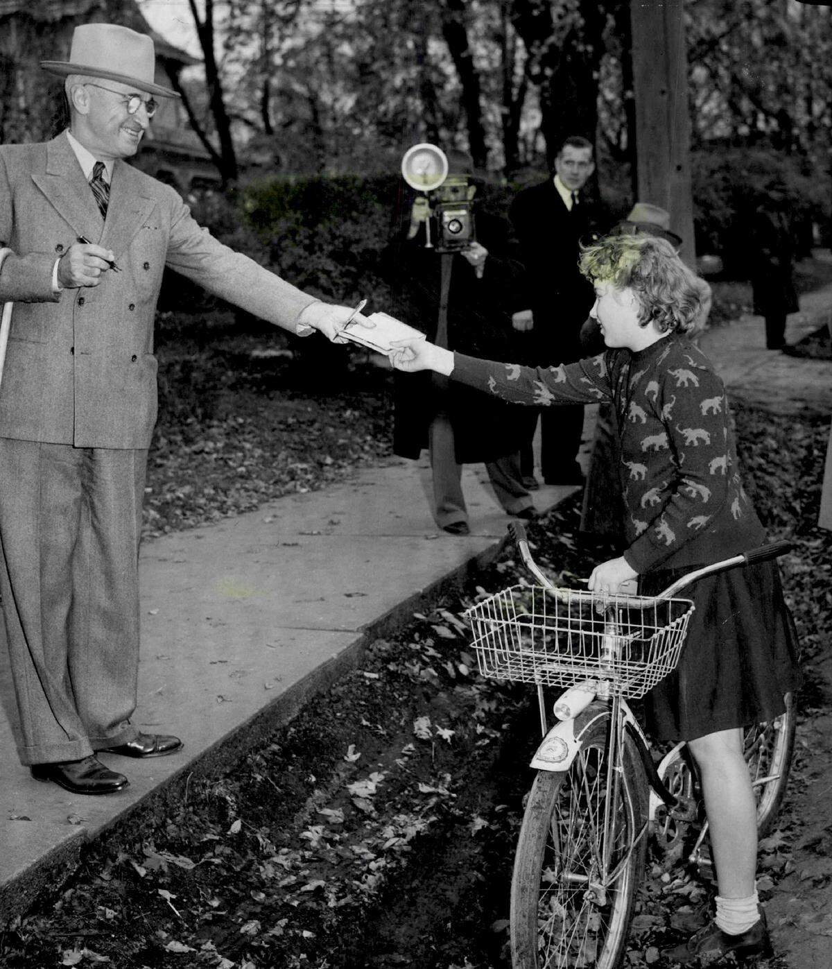 President Harry S. Truman returns a sheet of note paper with his autograph to 11-year-old Virginia Jennings of Independence after she caught up with him on Van Horn Road during his morning walk in 1946.