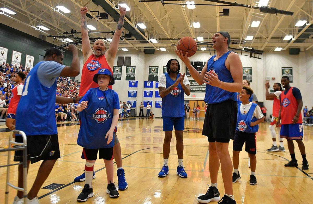 Jake Jones, middle, of Roeland Park, Kansas, lit up the crowd and a group of KU basketball alumni after scoring a basket during Thursday night’s Rock Chalk Roundball Classic at Free State High School in Lawrence. The annual game raises money for families fighting cancer. Jones is battling Burkitt’s Lymphoma.