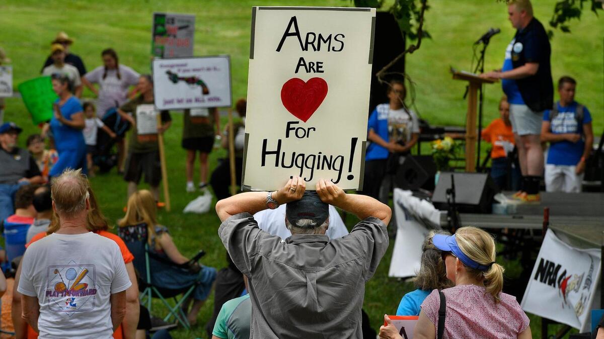 While LBGTQ community activist Jae Moyer, right rear, spoke to a crowd of about 350 people at Saturday’s March for Our Lives rally at Gillham Park, a spectator held up a sign denouncing the proliferation of assault weapons that are being used in mass shootings throughout the United States.