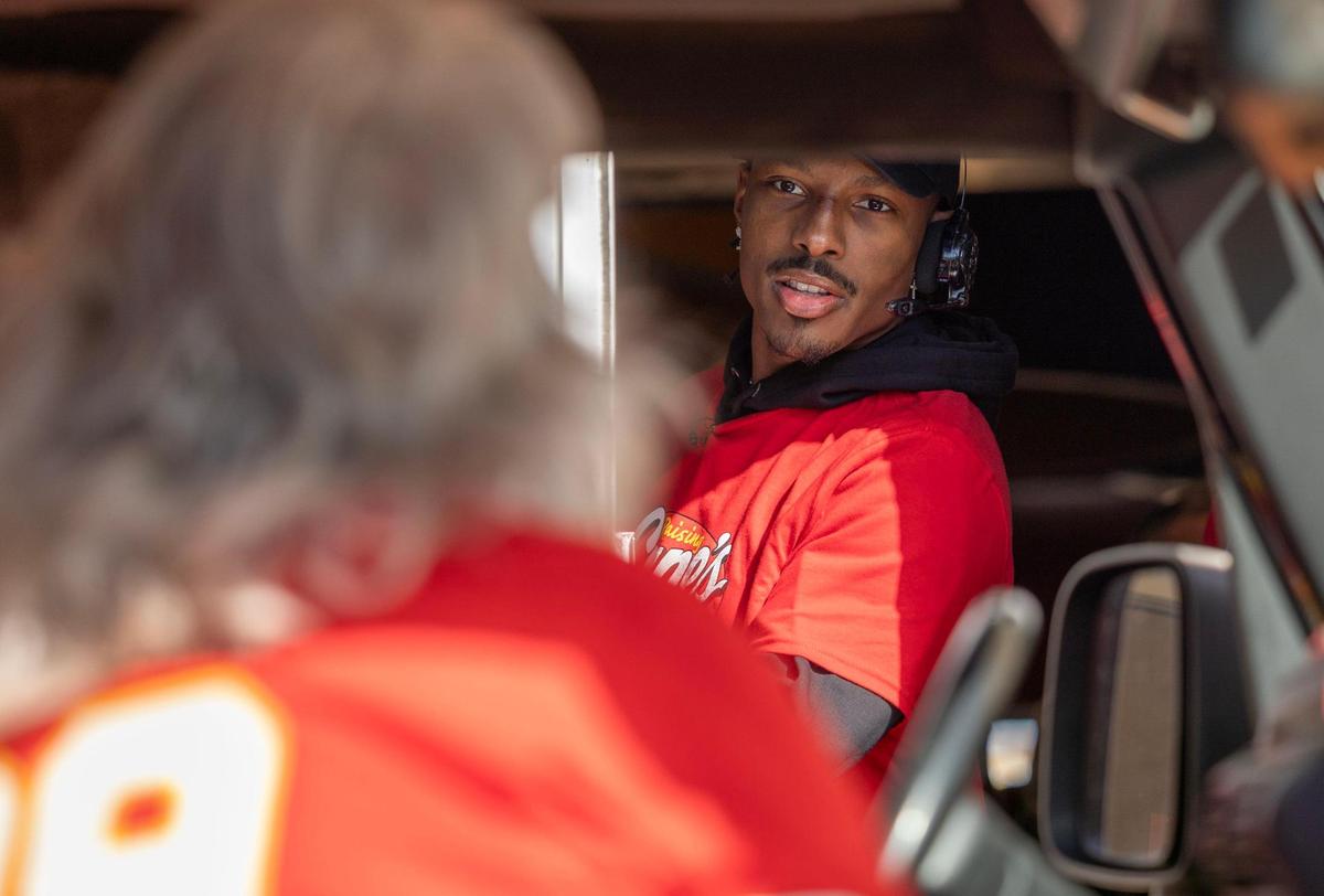 Kansas City Chiefs receiver Mecole Hardman Jr. talks to a customer while working the drive through at a Raising Cane’s restaurant in Blue Springs on Tuesday. Hardman was joined by teammate L’Jarius Sneed at the event.