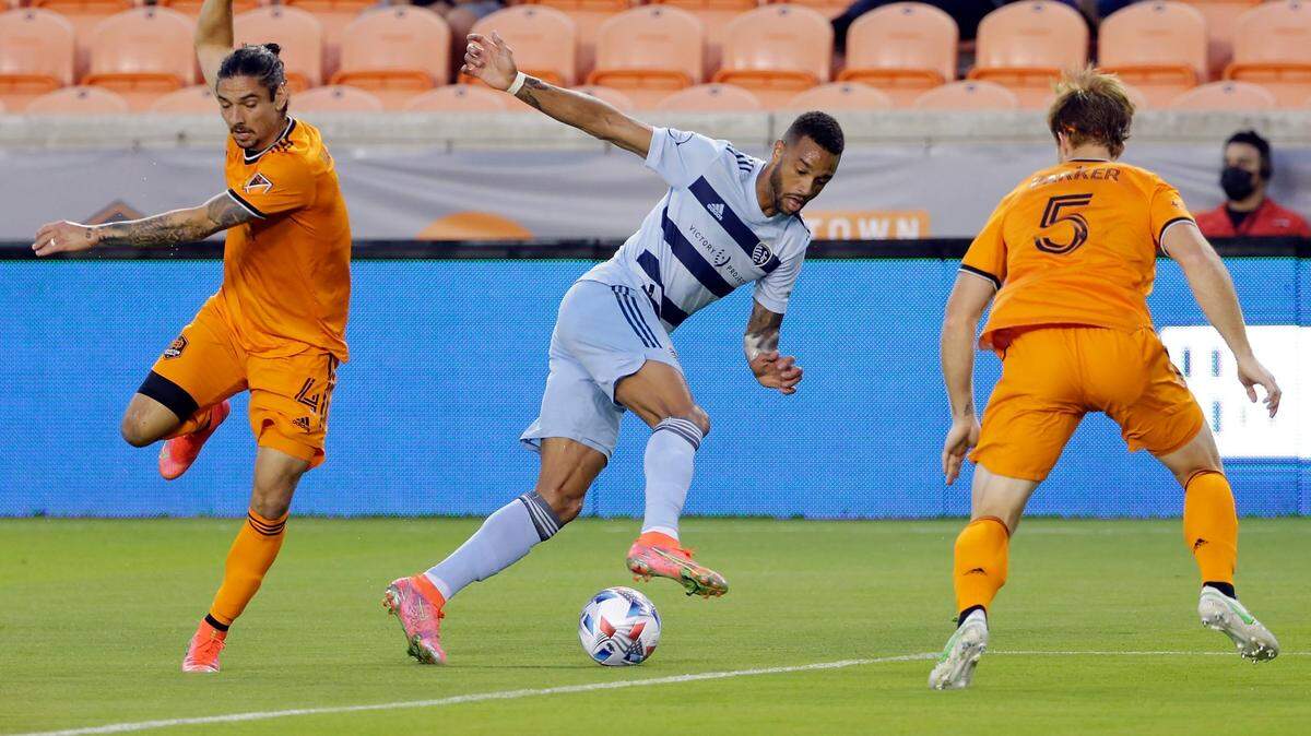 Sporting Kansas City forward Khiry Shelton, middle, moves the ball between Dynamo defenders Zarek Valentin, left, and Tim Parker Wednesday night in Houston.