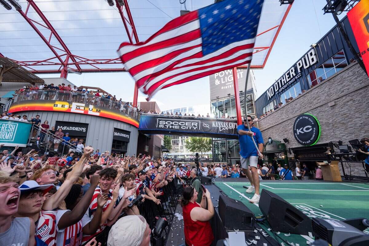 A man waves a flag as fans get hype before the USA team Round of 16 match vs. Belgium at the Power & Light District on Monday, July 6, 2026.