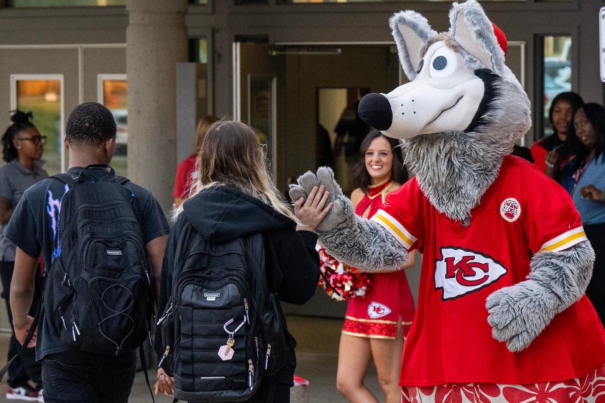 Kansas City Chiefs mascot K.C. Wolf high-fives students as he welcomes them to the first day of school at Central High School on Monday, Aug. 19, 2024, in Kansas City.
