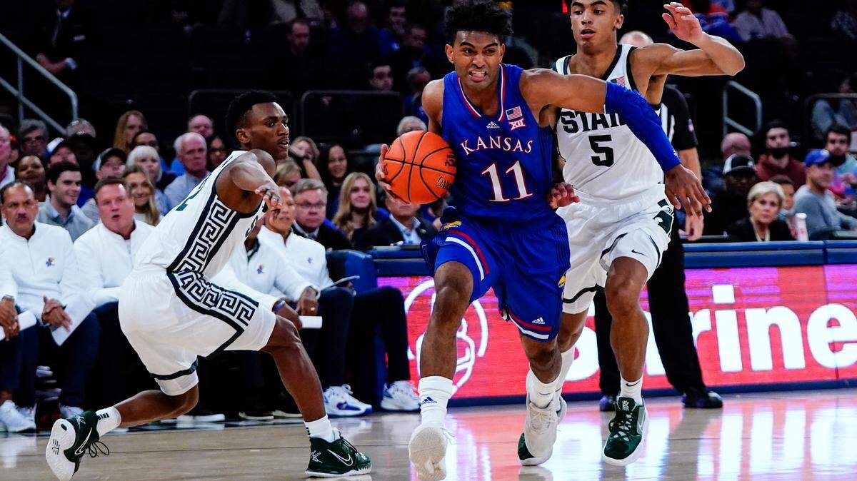 Kansas’ Remy Martin (11) drives past Michigan State’s Max Christie (5) and Tyson Walker during the second half of an NCAA college basketball game Tuesday, Nov. 9, 2021, in New York. (AP Photo/Frank Franklin II)