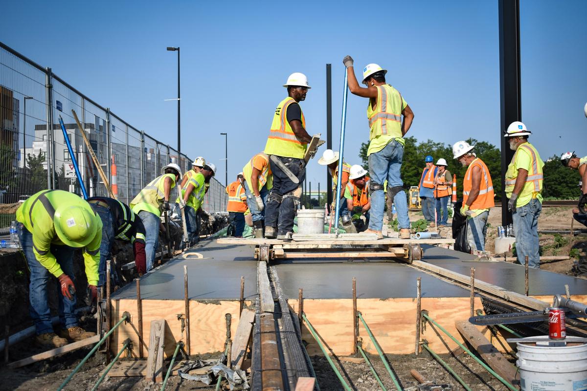 Construction workers smooth cement around newly laid streetcar tracks in Berkley Riverfront Park on Wednesday, July 10, 2024. The track slab is the first to be poured for the streetcar’s 0.7-mile riverfront extension.