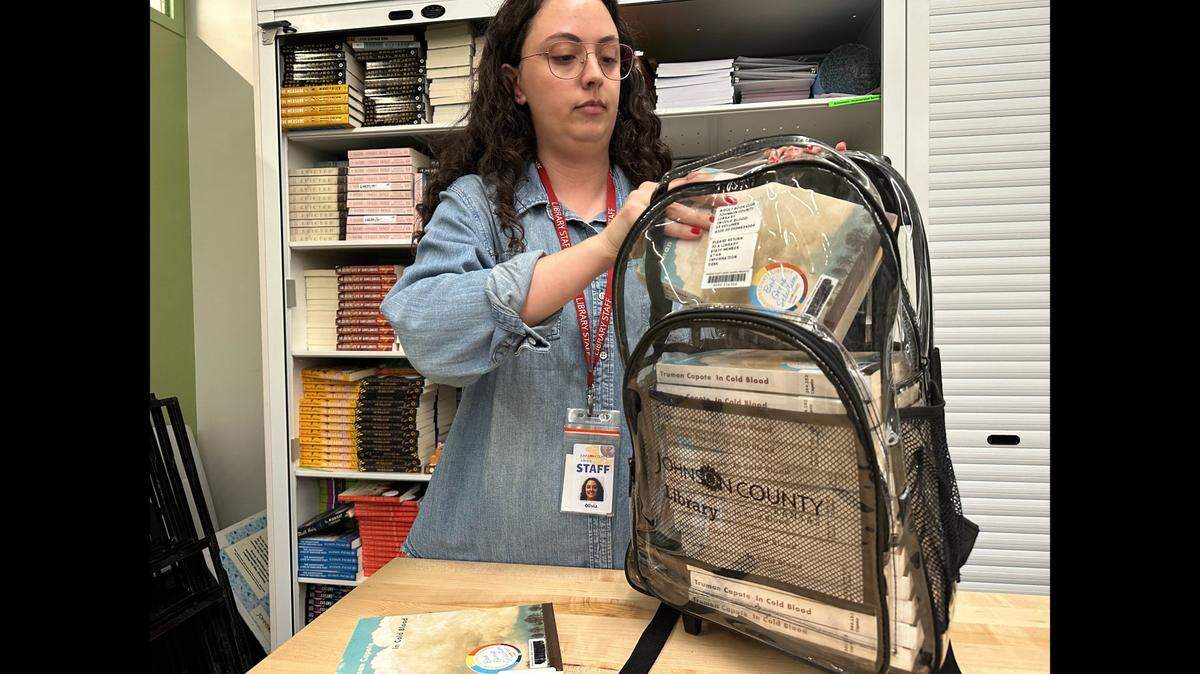 Johnson County Library patron service specialist Olivia Cusanelli packs book club kits in front of the library’s book club book selection storage cupboard.