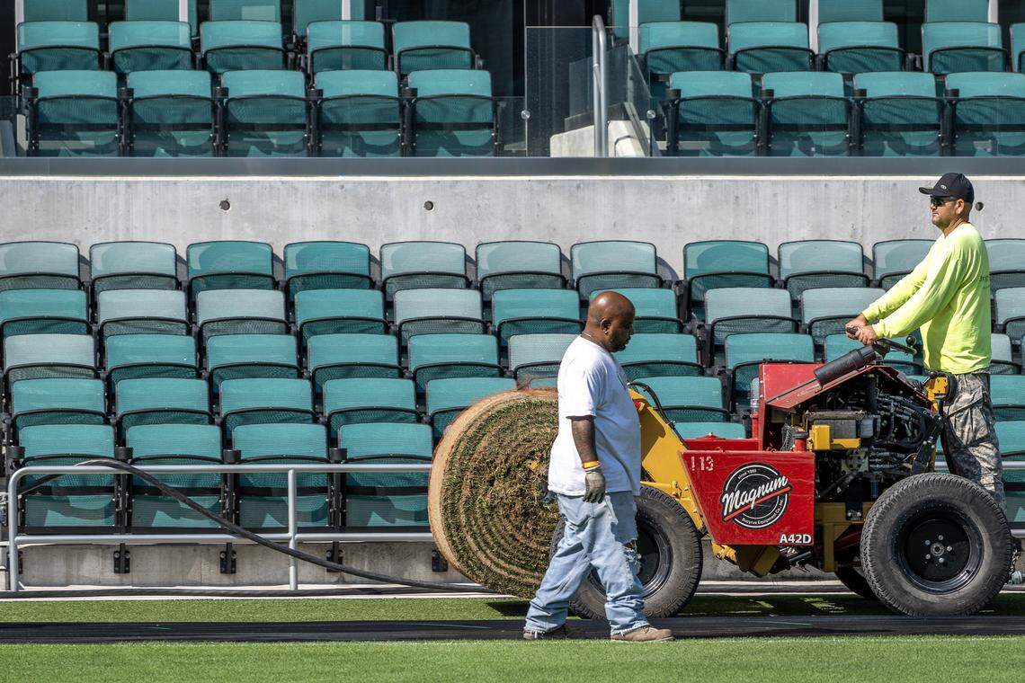 A Briggs Traditional Turf Farm crew member walks alongside a machine laying rolls of sod over artificial turf to convert the field for rugby at CPKC Stadium on Tuesday, April 14, 2026, in Kansas City.