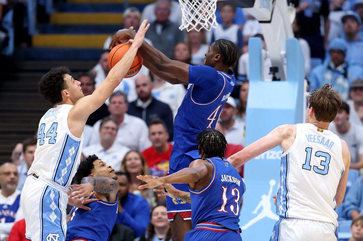 Kansas Jayhawks big manFlory Bidunga, center, battles North Carolina’s Luka Bogavac for a rebound during a men’s college basketball game at the Dean E. Smith Center in Chapel Hill, N.C., on Friday, Nov. 7, 2025.