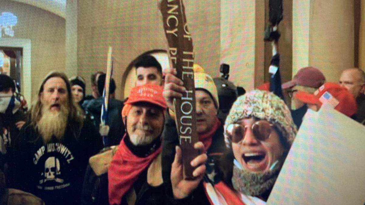 William Merry (red cap), Paul Westover (yellow stocking cap, behind sign) and Emily Hernandez (wearing sunglasses) during the U.S. Capitol invasion on Jan. 6, 2021.