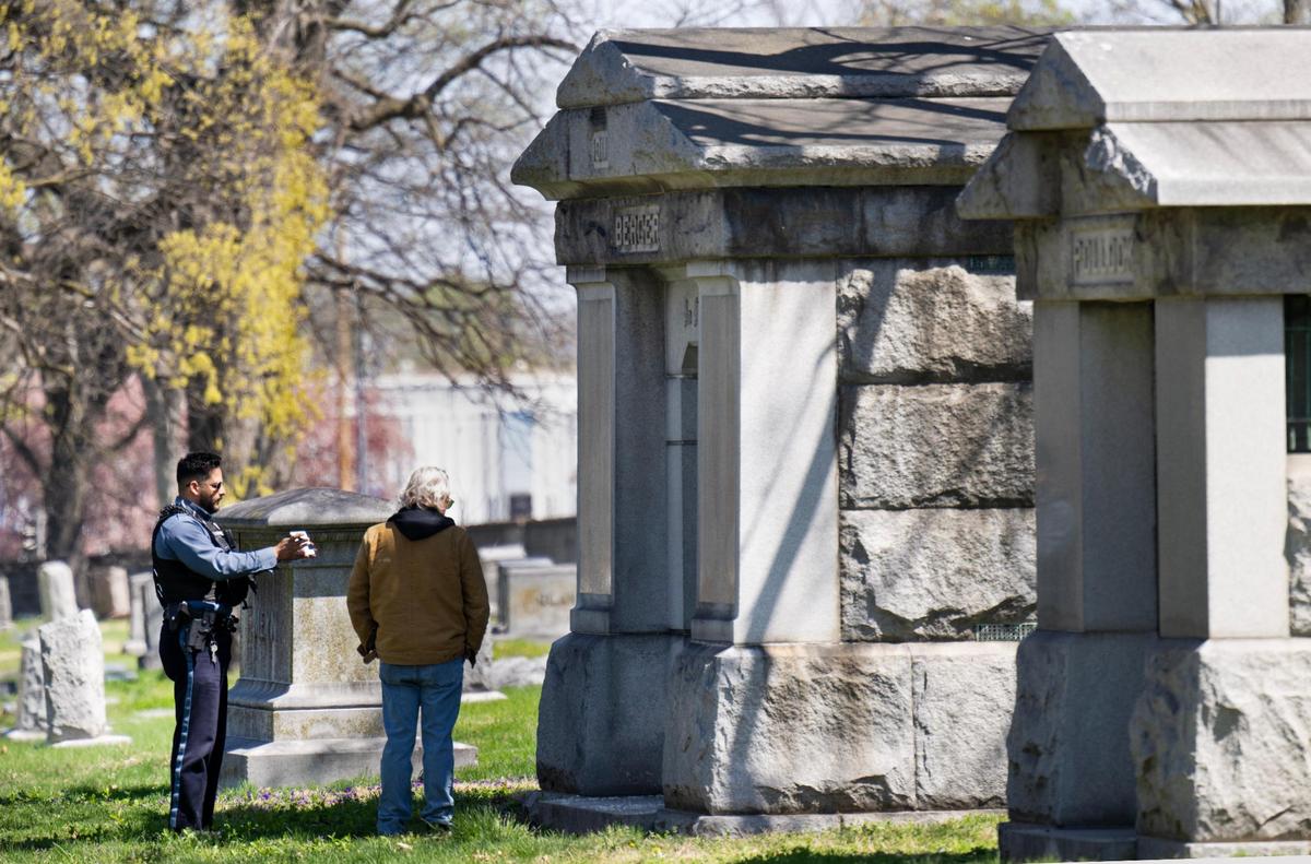 A Kansas City Police officer, responding to a vandalism report, looked over damage to a mausoleum with a board member at the historic Elmwood Cemetery on Tuesday, April 8, 2025, in Kansas City.