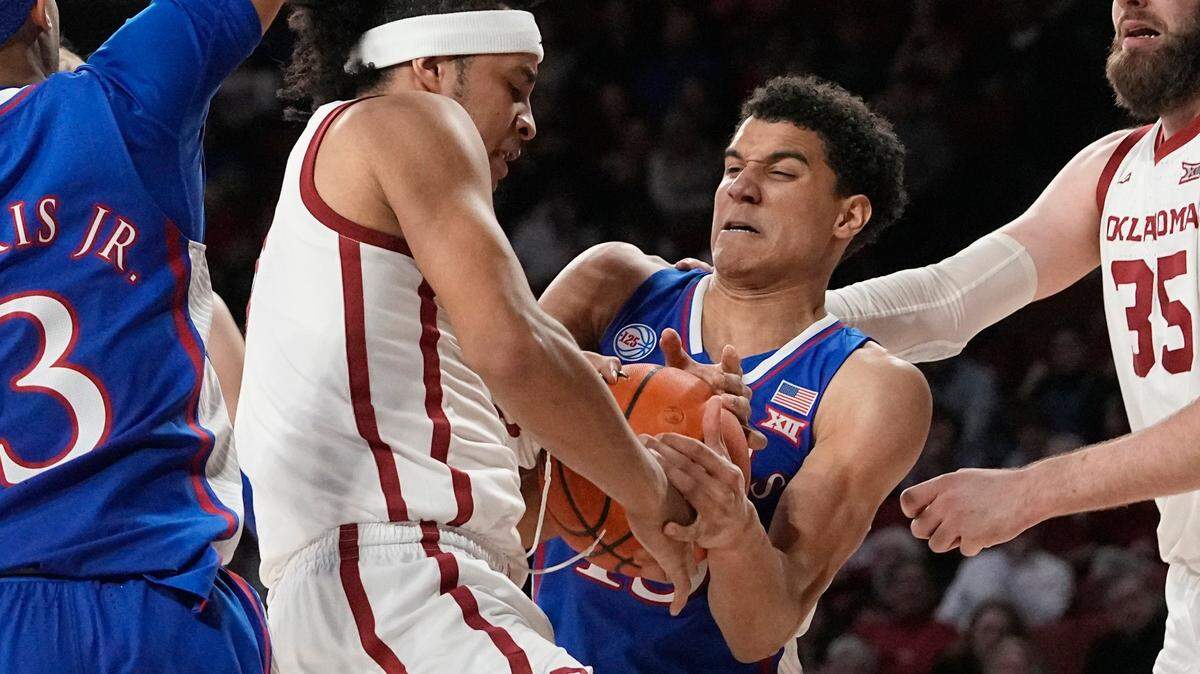 Oklahoma forward Jalen Hill, left, and Kansas guard Kevin McCullar Jr., right, fight for control of the ball in the second half of a game Saturday, Feb. 11, 2023, in Norman, Okla.
