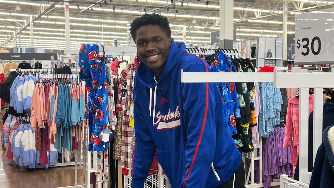 Kansas freshman forward Flory Bidunga pedals a bicycle through Walmart on Sunday night. He and his 18 Jayhawk teammates spent an hour shopping for families in need.