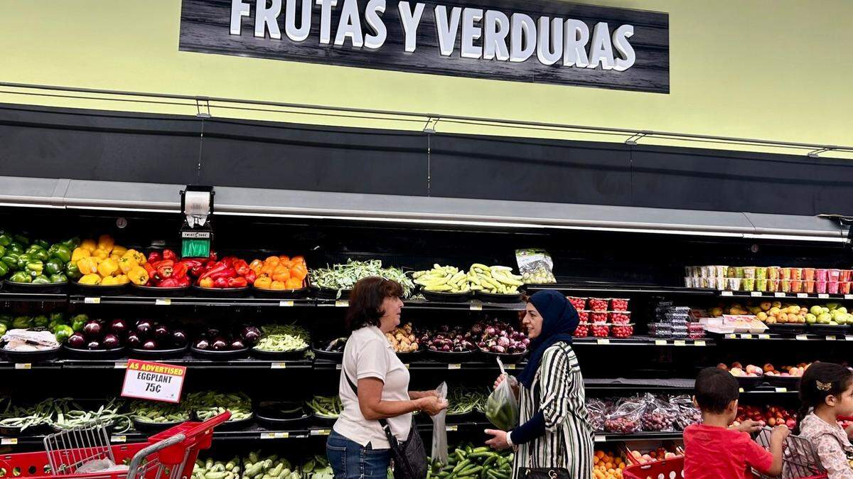 Two women chat while grabbing produce from World Fresh Market in Overland Park.