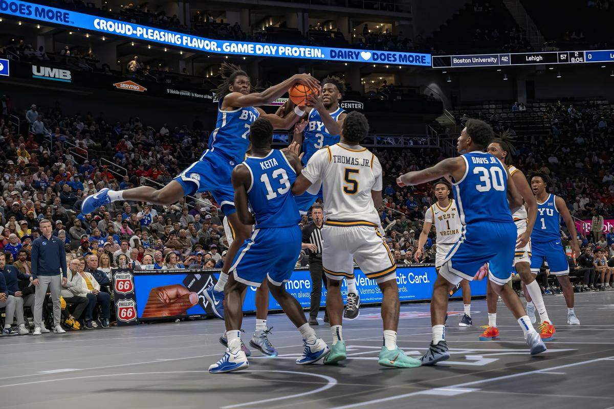 BYU Cougars forward Khadim Mboup (7) and BYU Cougars forward AJ Dybantsa (3) go for the ball in front of West Virginia Mountaineers forward DJ Thomas (5) during the second half of the Big 12 Men's Basketball Tournament at T-Mobile Center on Wednesday, March 11, 2026, in Kansas City.