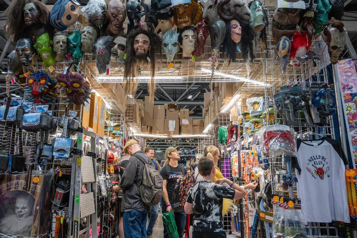 Guests walk through a booth full of masks while attending the 25th anniversary of Planet Comicon at the Kansas City Convention Center on Saturday, March 9, 2024, in Kansas City.