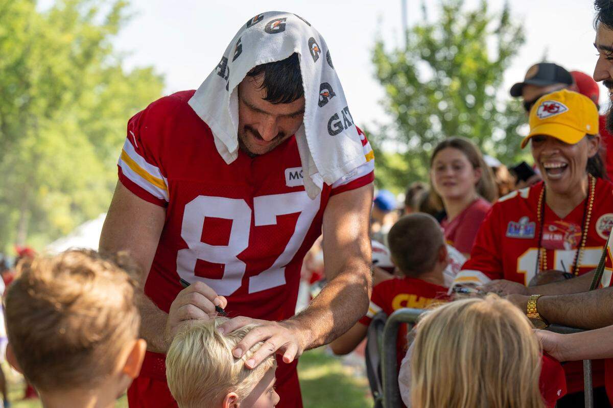 Kansas City Chiefs tight end Travis Kelce jokingly pretends to sign a young fan’s head at training camp.