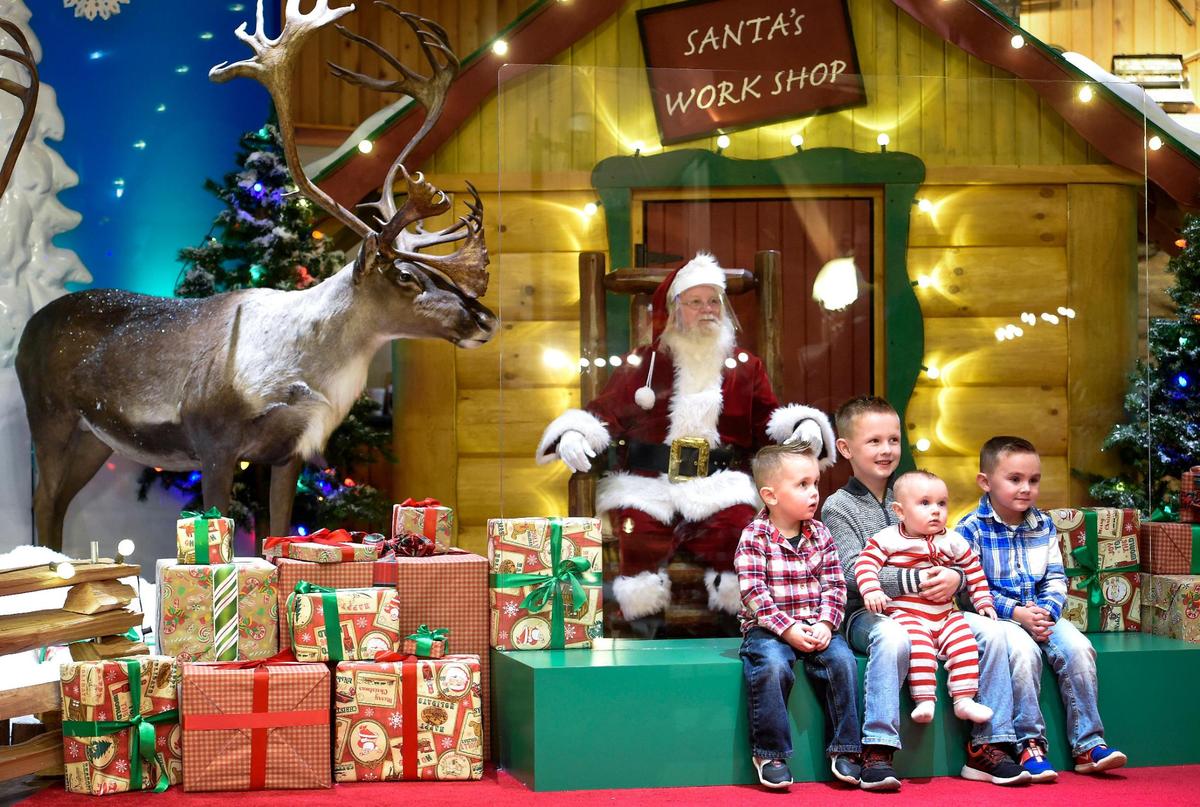The children of Nathan and Marcie Baker of Platte City, including Asher, 2, from left, Branden, 6, Elijah, 7-months, and Jace Baker, 4, had their photos taken with Santa, also known as Ricky Kell, who sat behind a plexiglass shield at Cabela’s on Wednesday, Dec. 2, 2020, in Kansas City, Kansas. Cabela’s is taking reservations to visit Santa and is operating with COVID-19 precautions in place. The visits with Santa include temperature checks, masks, and sanitizing after each guest.