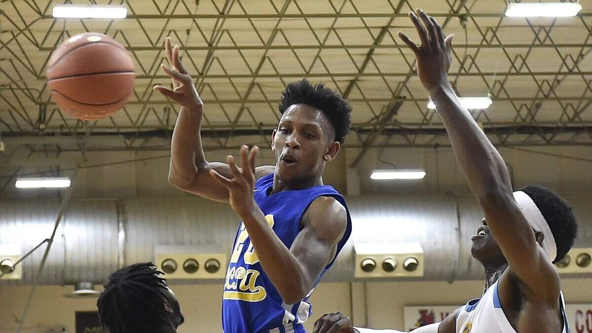 Lincoln Prep senior Antoin Burton passes over Grandview’s Liashwuon Boston (12) and Kamto Eze (33) in the second quarter of a first-round game on Wednesday at the annual William Jewell basketball tournament. Grandview won 70-44.