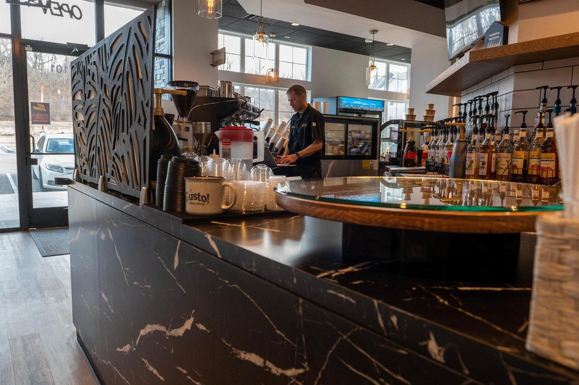 Adam Kintop prepares for customers at Gusto Coffee Shop at Creekside development in Parkville.