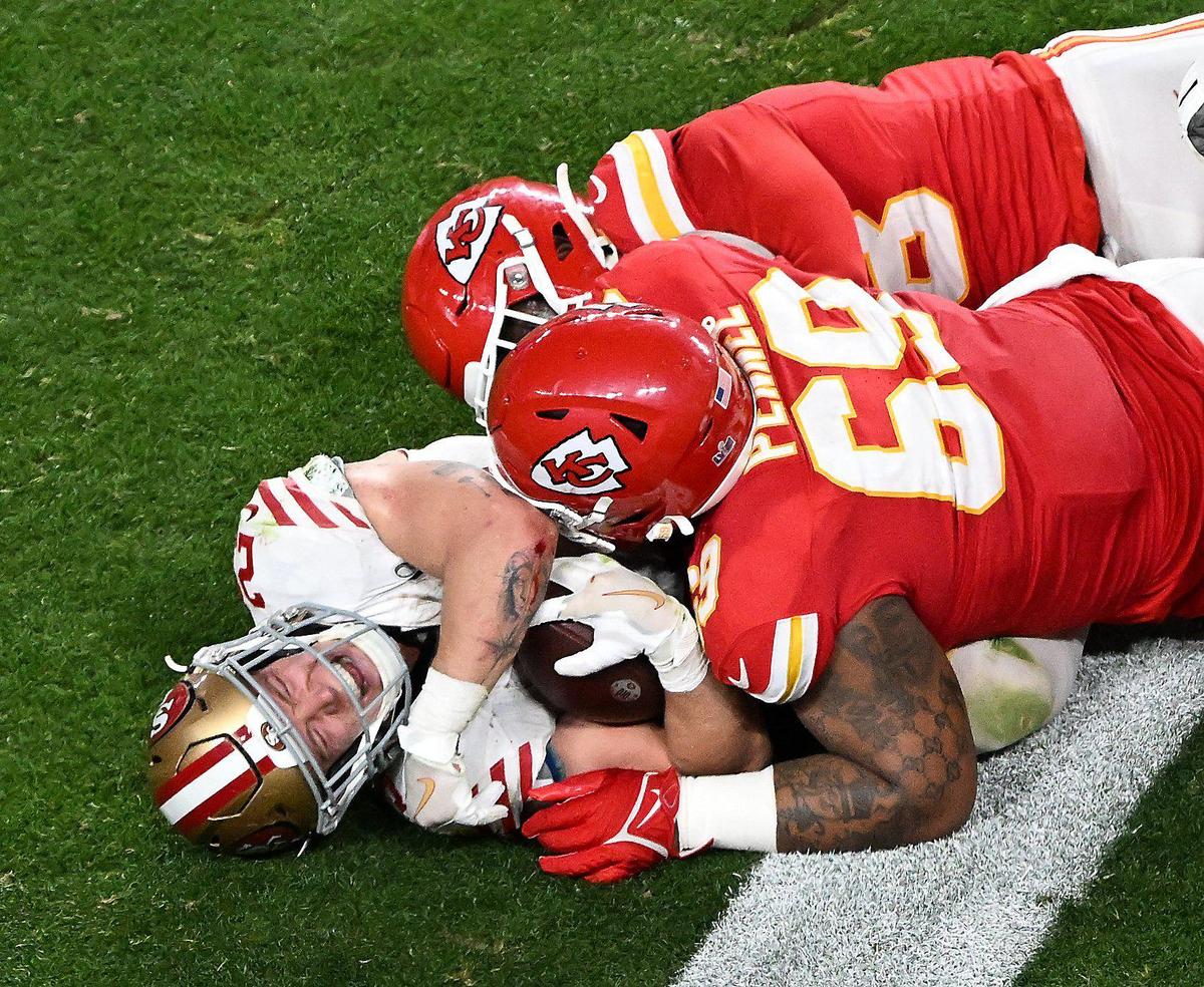 San Francisco 49ers running back Christian McCaffrey (23) is crushed by Kansas City Chiefs defensive tackle Mike Pennel Jr. (69) in the fourth quarter of Super Bowl LVIII, Sunday, Feb. 11, 2024, in Las Vegas.