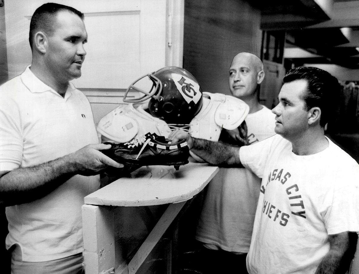 Chiefs’ tackle John Fritsch, left, receives his equipment from trainer Wayne Rudy, center, and Bobby Yarborough, equipment manager, right, in 1965.