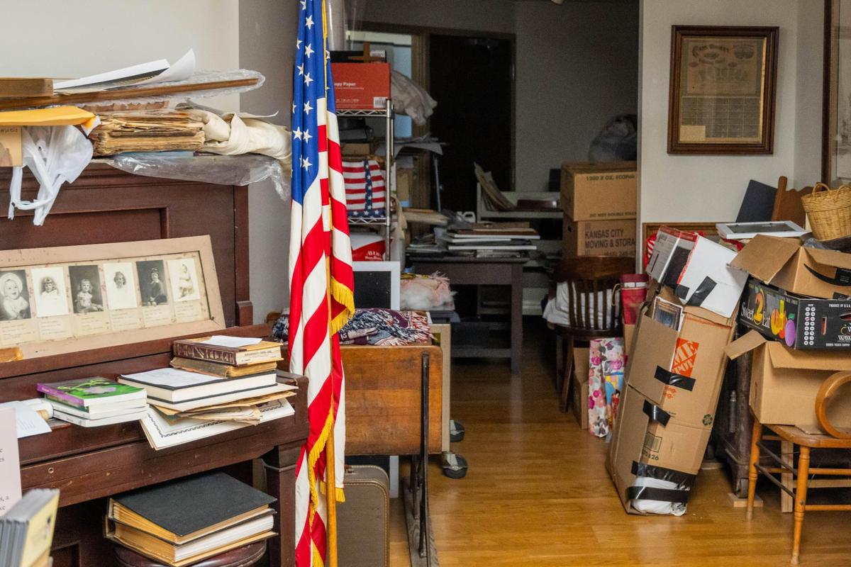 Piles of donations sit in the office of the Cass County Historical Society located at the Cass County Public Library Harrisonville Branch on Thursday, Mar. 20, 2025. The archives recently lost their IMLS, Institute of Museum and Library Services, grant due to budget cuts by the Trump administration. The money was to be used to pay interns to help process donations to the archives.