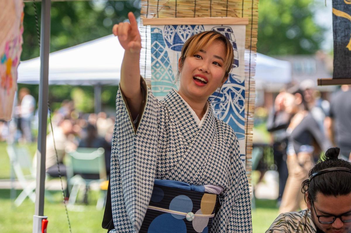 Madoka Koguchi, shows a customer her art pieces at the Saranya Hubbard booth during the AAPIconic Festival on Saturday, May 20, 2023, in Kansas City.