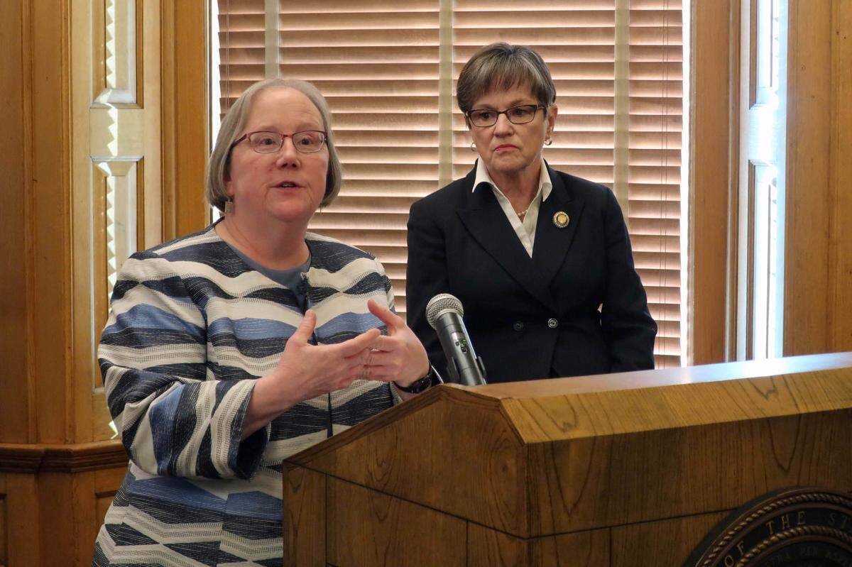 Laura Howard, left, the top social services administrator in Kansas state government, discusses a plan to merge two agencies as Gov. Laura Kelly, right, watches, during a news conference, Wednesday, Jan. 8, 2020, at the Statehouse in Topeka, Kansas. Howard is secretary for both the Department for Children and Families and the Department for Aging and Disability Services, which would be merged. (AP Photo/John Hanna)