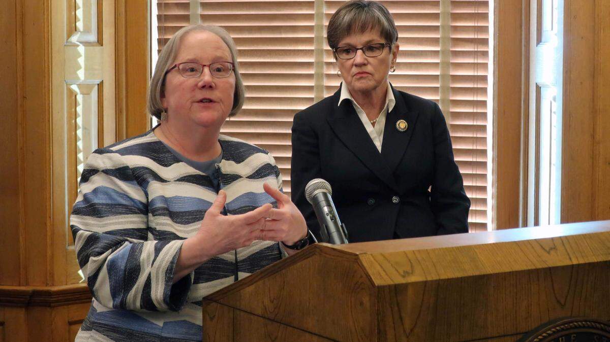 Laura Howard, left, the top social services administrator in Kansas state government, discusses a plan to merge two agencies as Gov. Laura Kelly, right, watches, during a news conference, Wednesday, Jan. 8, 2020, at the Statehouse in Topeka, Kansas. Howard is secretary for both the Department for Children and Families and the Department for Aging and Disability Services. (AP Photo/John Hanna)