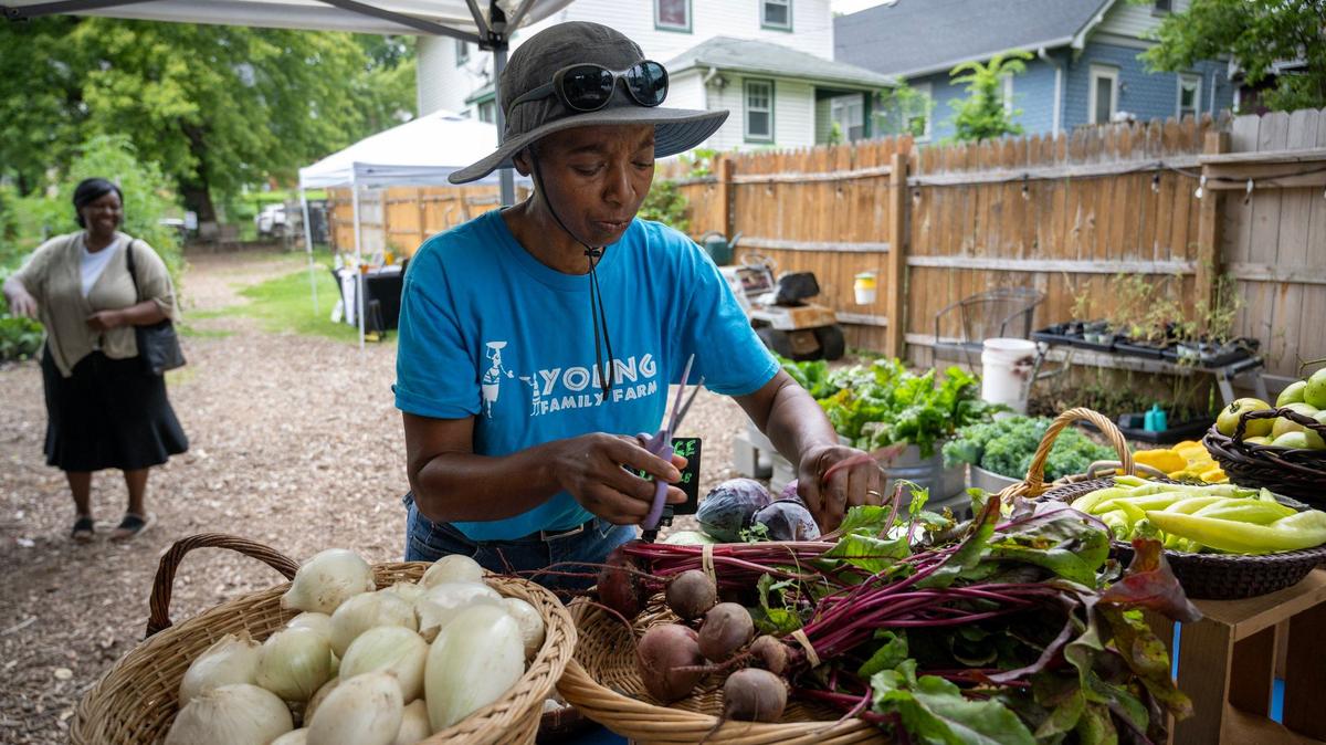 Yolanda Young of The Young Family farm, trims greens on beets to sell at their weekly farmers market event on Saturdays.