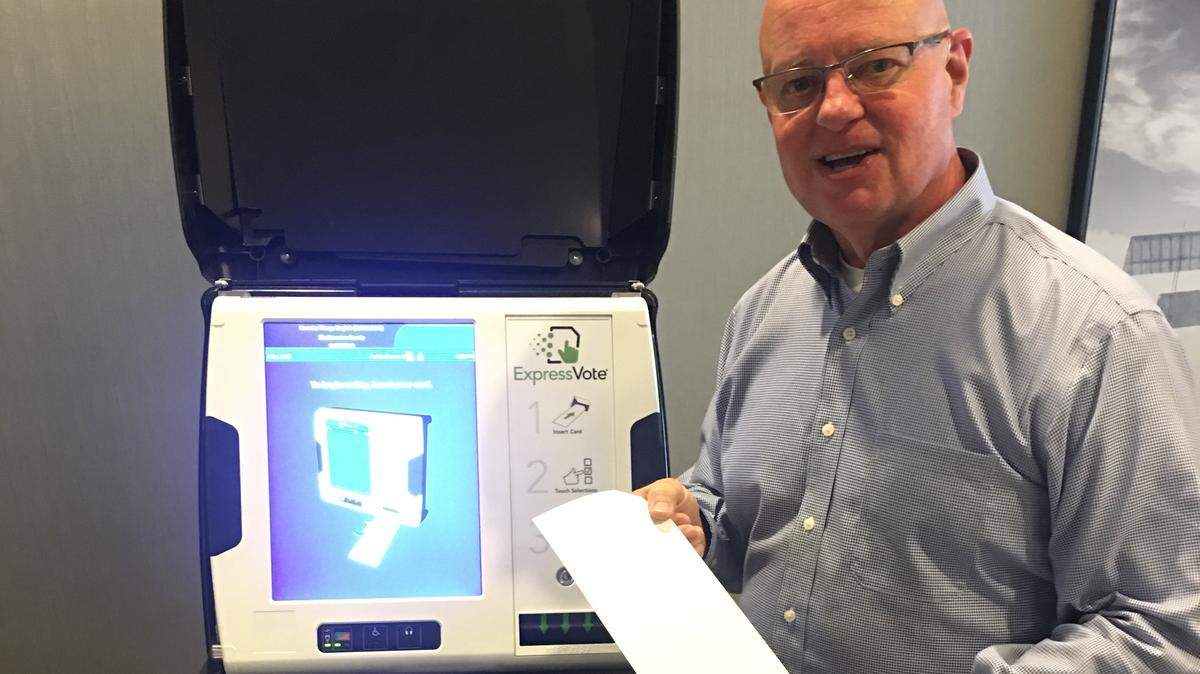 Johnson County Election Commissioner Ronnie Metsker demonstrates the new voting machines with paper ballots.