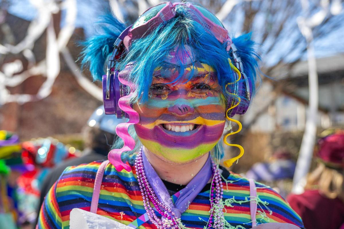 Ollie Clark, adorned in colorful face paint and wearing vibrant attire, smiles as she stands for a portrait during the Krewe de Prank parade on Sunday, March 2, 2025, in Kansas City.