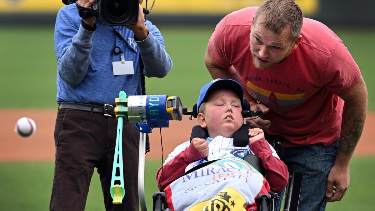 Kayden Rhoades was given 24 hours to live at birth, but 15 years later he threw out the first pitch on Thursday at Kauffman Stadium with the help of his family. Rhoades, who was born with hydranencephaly, used a device his father Dustin created for him to complete the feat. It was a bucket-list day in every way for the family from Sioux City, Iowa.
