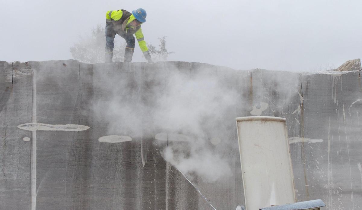 Cody Wells adjusted a water hose to keep the diamond-laced cutting band from overheating as it cut a block of 350-million-year-old limestone from a ledge at Phenix Marble Co. quarry near Ash Grove, Missouri.