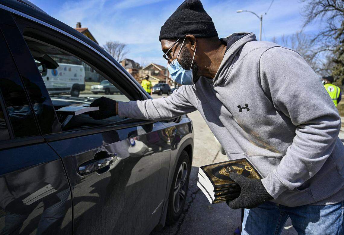 Imam Jihad Mu’Min hands out Qurans to people as they pickup food at a food distribution event in O’ Fallon Park in O’ Fallon on Saturday, Feb. 27, 2021. Every week Al-Mu’minun Islamic Center works with Zakat Foundation of America to donate food to approximately 1000 families in the St. Louis area. People are able to take as many boxes as they need and each truck brings about 1000 boxes a week.