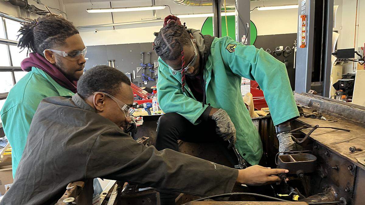 Working on 1973 Bronco: DaJuan Barrett (left) Marcus Taylor (right) with (in black) Damon King, an instructor from Mind Drive, which partners with Ignition Lab from Operation Breakthrough