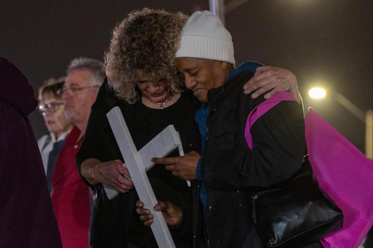 Barbara Scott, right, is embraced by a community member as she holds a cross in memory of her son, Donald Scott, during a vigil on at The Gathering Church on Thursday, Dec. 21, 2023, in Independence, Missouri. Community members gathered to honor the lives of homicide victims in Kansas City for 2023, uniting to read the names of these individuals, reflect on their legacies, and offer support to those grieving the loss of their loved ones.
