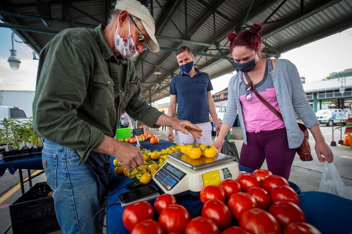 Gary Oberdiek of River’s Edge Produce in Platte City, weighed yellow tomatoes for Chris Fasl and Ashley Durkin of Kansas City when the couple stopped to buy produce Saturday, May 8, at the City Market in Kansas City.