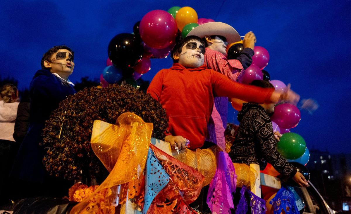 Children throw candy from a float during the Dia de los Muertos parade hosted by the Central Avenue Betterment Association on Saturday in Kansas City, Kan.